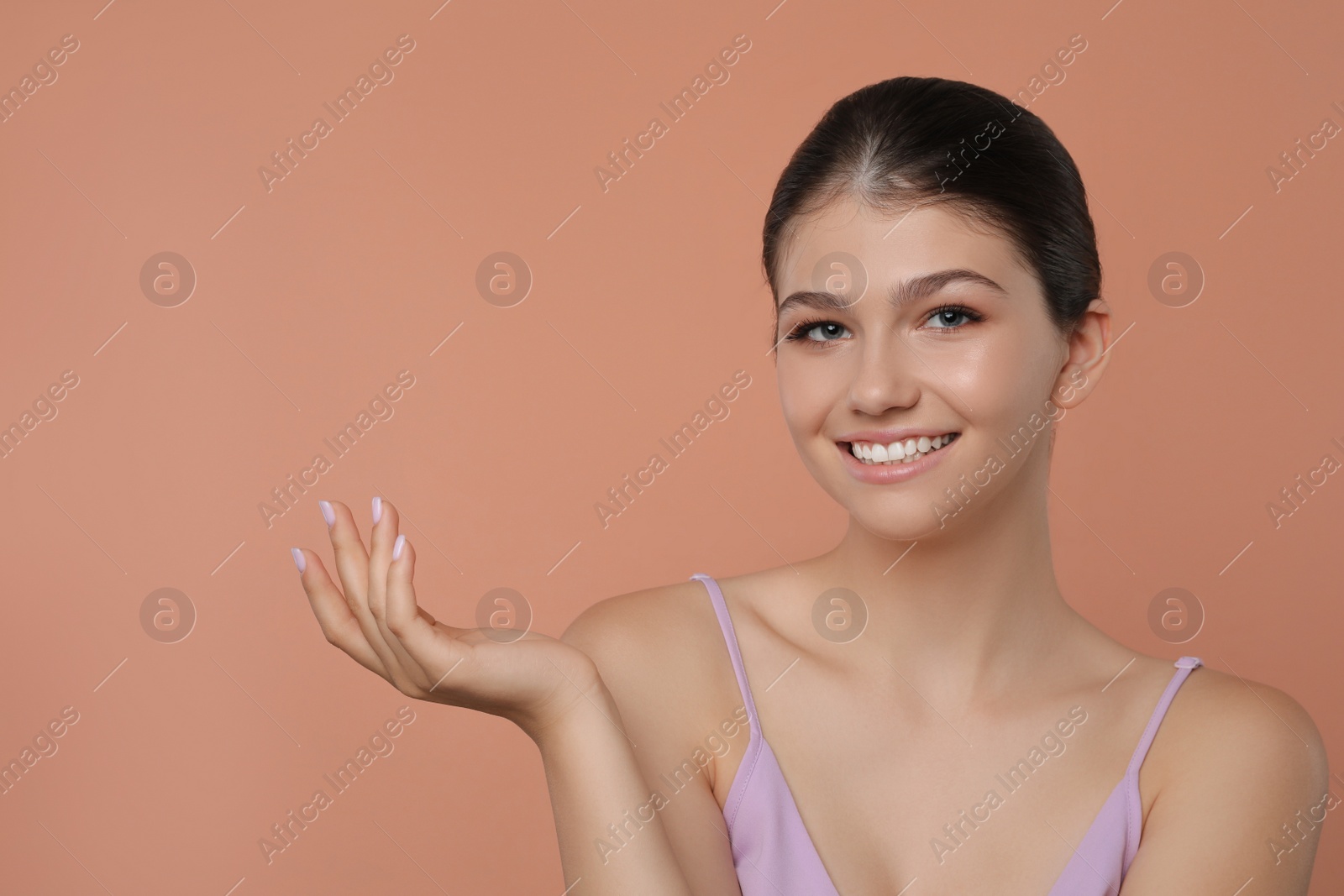 Photo of Portrait of pretty girl on pale coral background, space for text. Beautiful face with perfect smooth skin