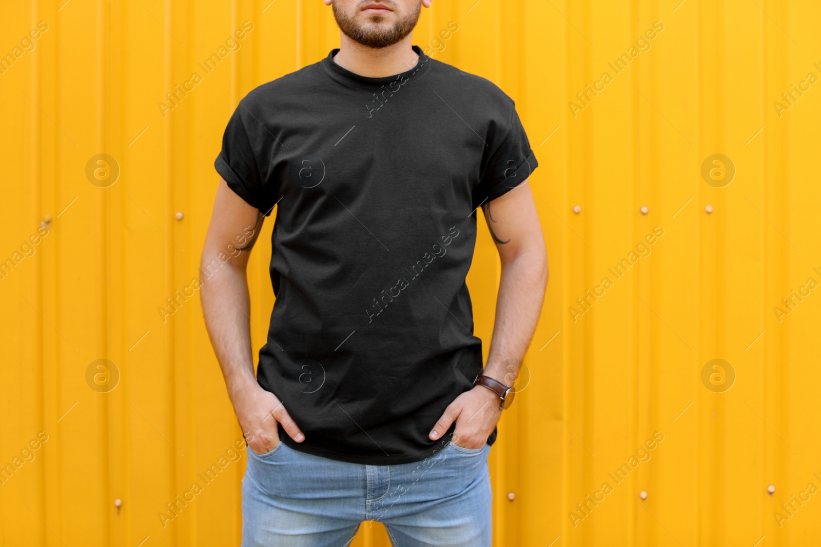 Photo of Young man wearing black t-shirt near color wall on street