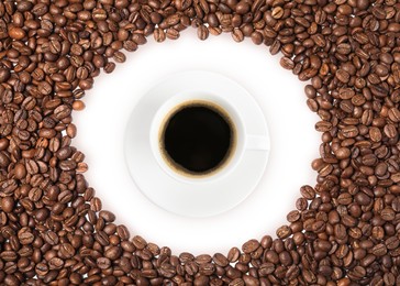 Cup of tasty espresso and roasted coffee beans on white background, flat lay