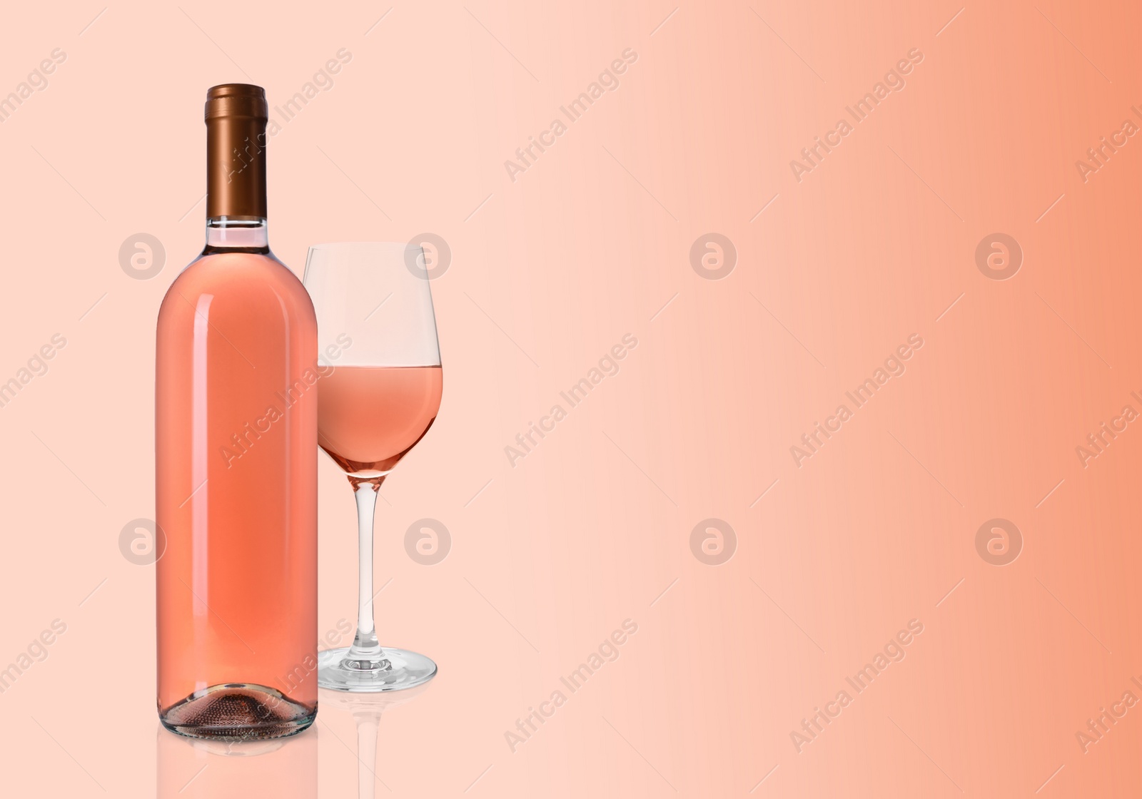 Image of Bottle and glass of delicious rose wine on pink background. Space for text