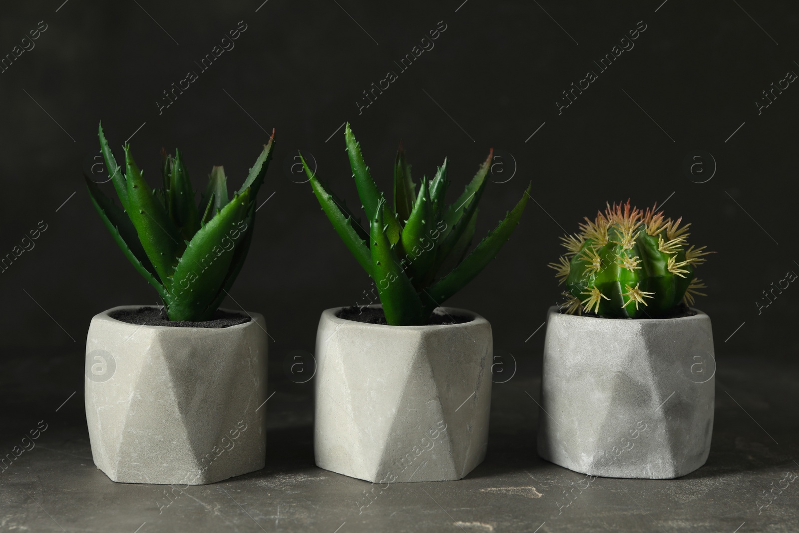 Photo of Artificial plants in flower pots on grey stone table