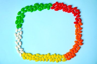 Photo of Frame of jelly beans on color background, top view. Space for text