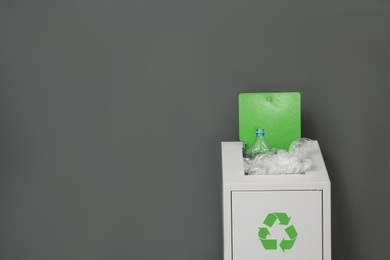 Photo of Metal bin with garbage on grey background, space for text. Waste recycling