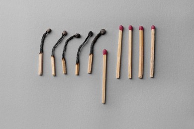 Photo of Burnt and whole matches on light grey background, flat lay