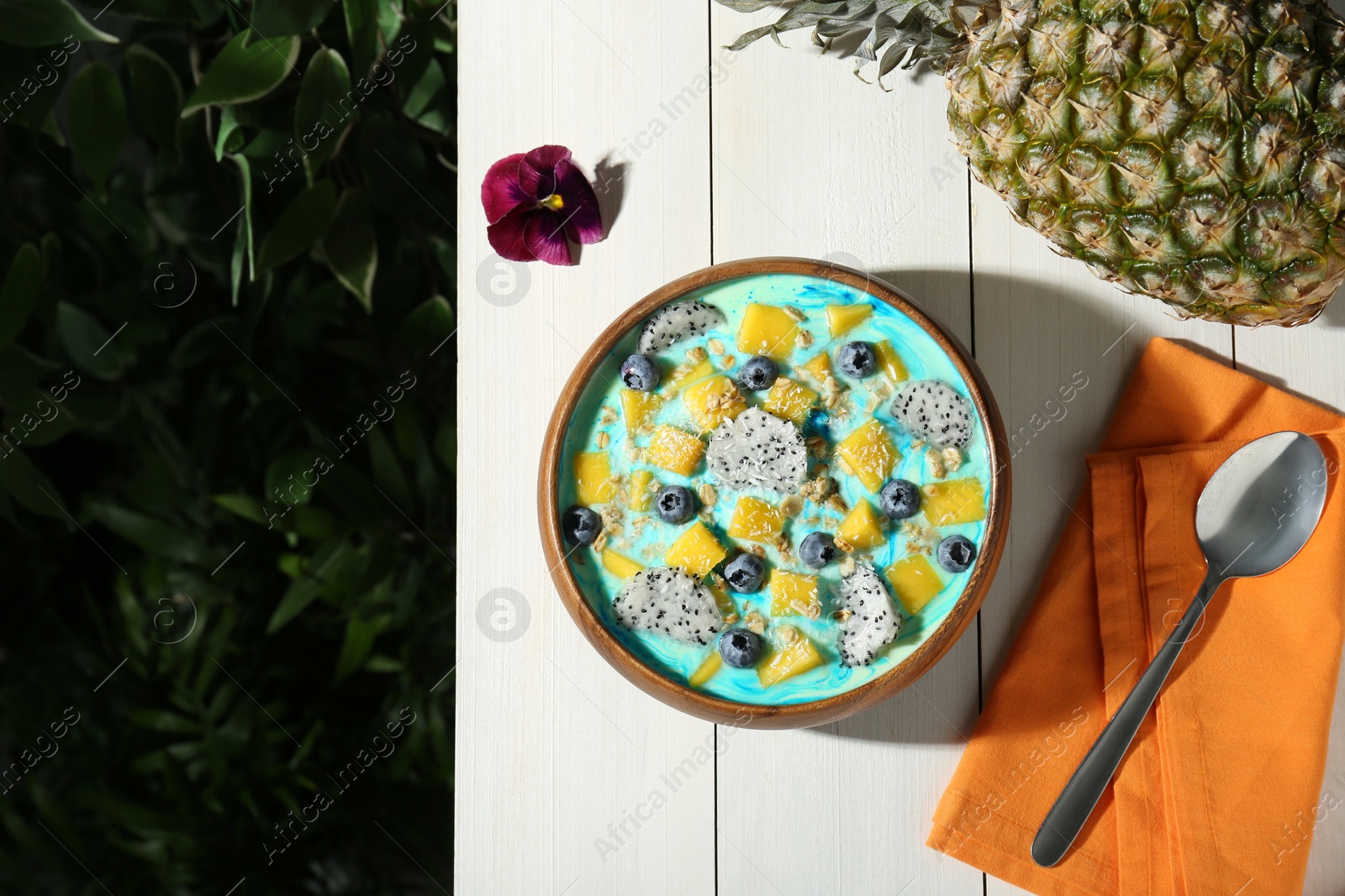 Photo of Delicious smoothie bowl with fresh fruits, blueberries and oatmeal served on white wooden table outdoors, flat lay. Space for text