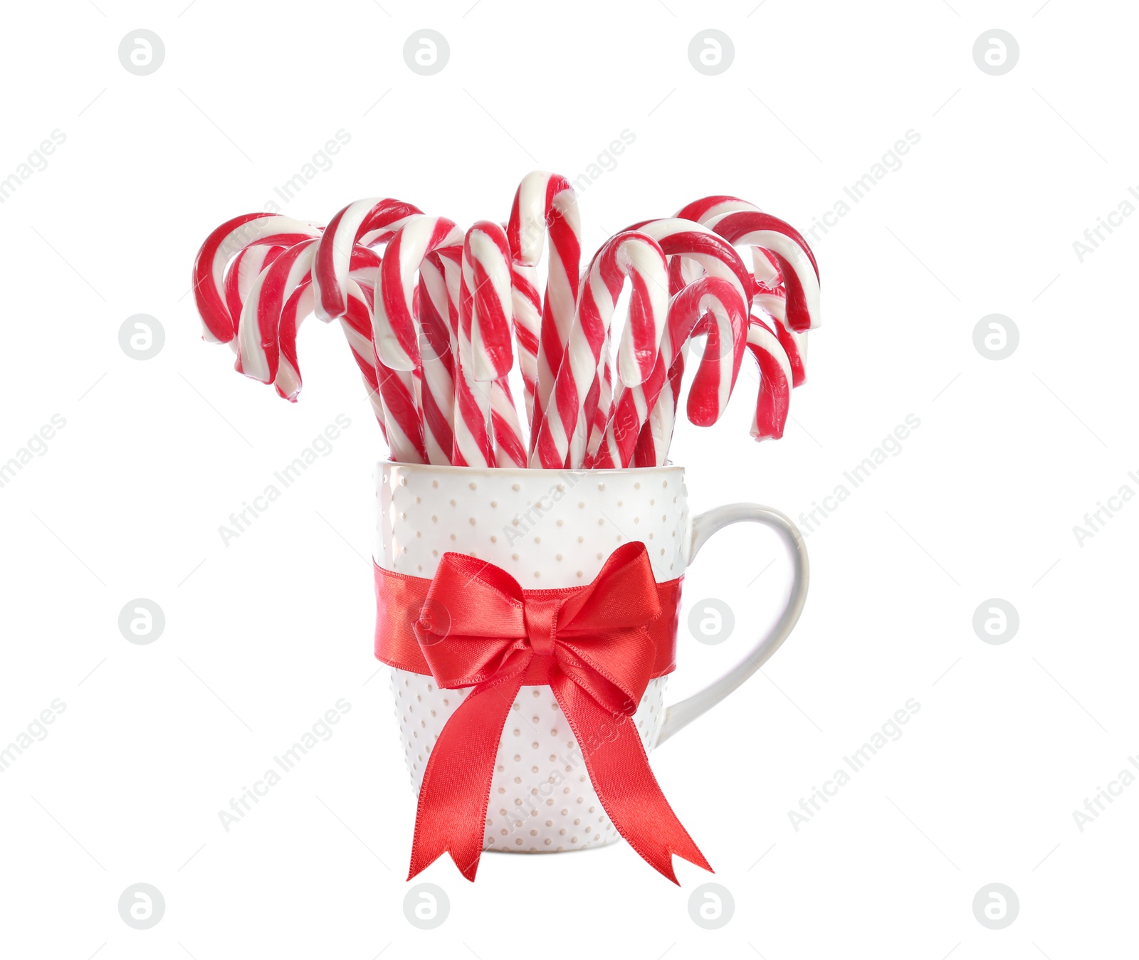 Image of Many sweet candy canes in cup with red bow on white background. Christmas treat