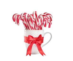 Many sweet candy canes in cup with red bow on white background. Christmas treat