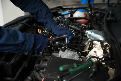 Photo of Technician checking modern car at automobile repair shop, closeup