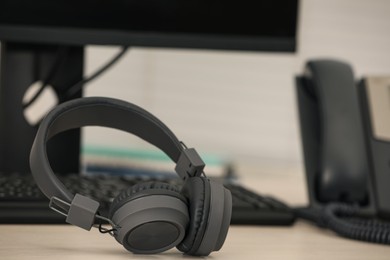 Modern headphones, desktop telephone and computer on table indoors, space for text