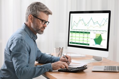 Professional accountant working at wooden desk in office