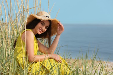Beautiful young woman wearing straw hat on beach. Stylish headdress