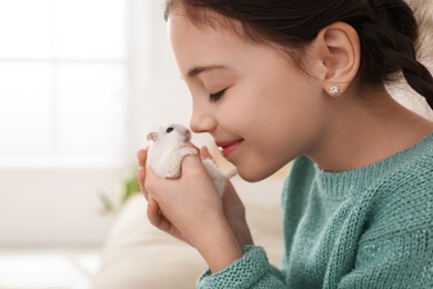 Little girl with cute hamster at home