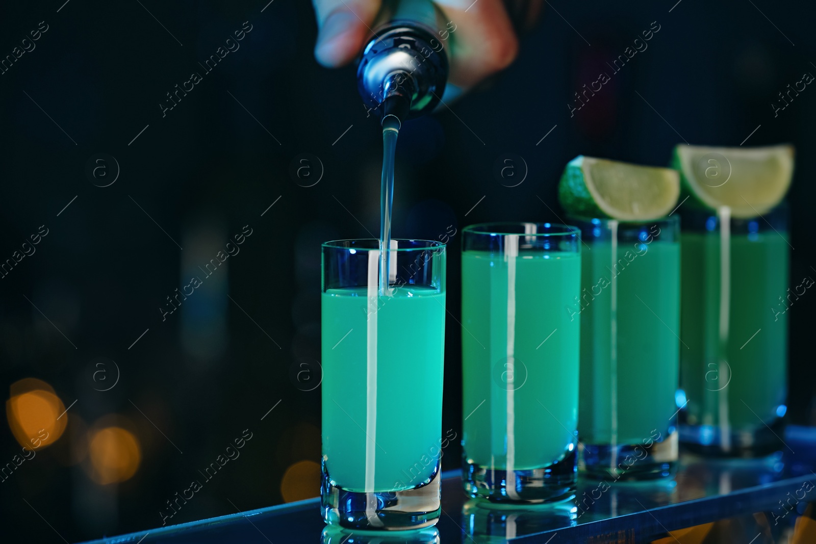 Photo of Bartender pouring alcohol drink into shot glass on blurred background, closeup. Space for text