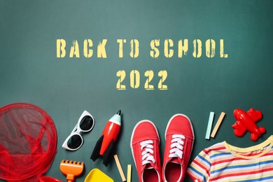 Back to school 2022. Different child accessories on green chalkboard, flat lay