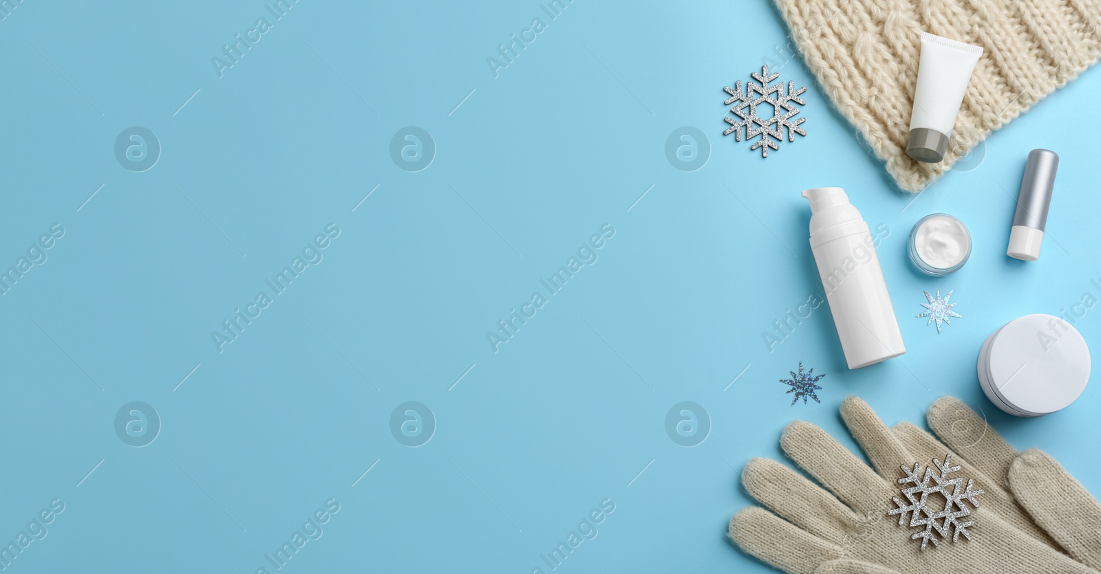 Photo of Flat lay composition with different cosmetic products on light blue background, space for text. Winter care