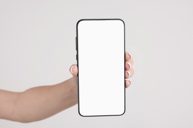 Photo of Woman holding smartphone with blank screen on light grey background, closeup. Space for text