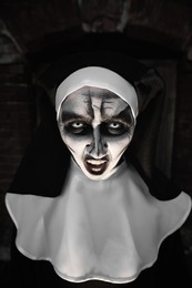 Photo of Portrait of scary devilish nun outdoors. Halloween party look