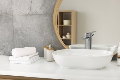 White vessel sink, mirror and different personal care products on bathroom counter. Interior design