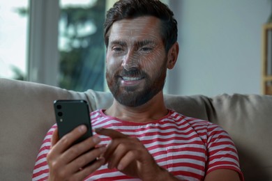 Image of Man using smartphone with facial recognition system at home. Security application scanning his face for approving owner's identity