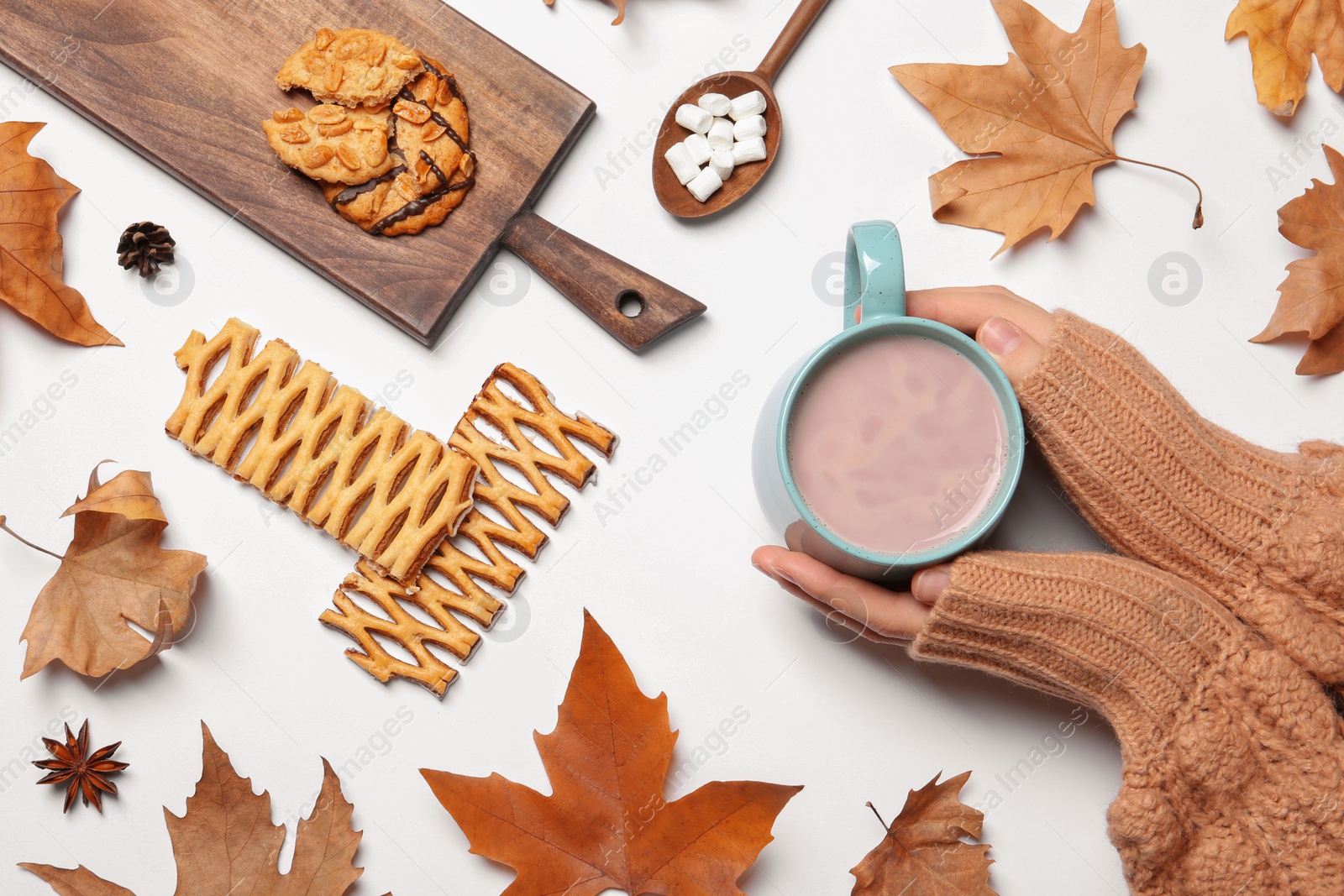 Photo of Woman in autumn sweater holding hot cozy drink on white background, top view