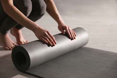 Woman rolling yoga mat in studio, closeup