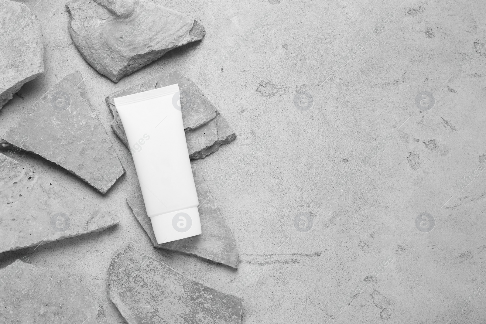 Photo of Flat lay composition with tube of hand cream and stones on grey background. Mockup for design