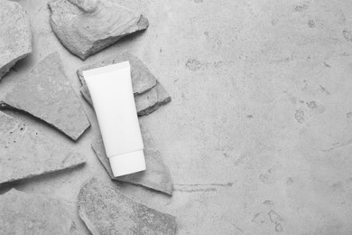 Photo of Flat lay composition with tube of hand cream and stones on grey background. Mockup for design