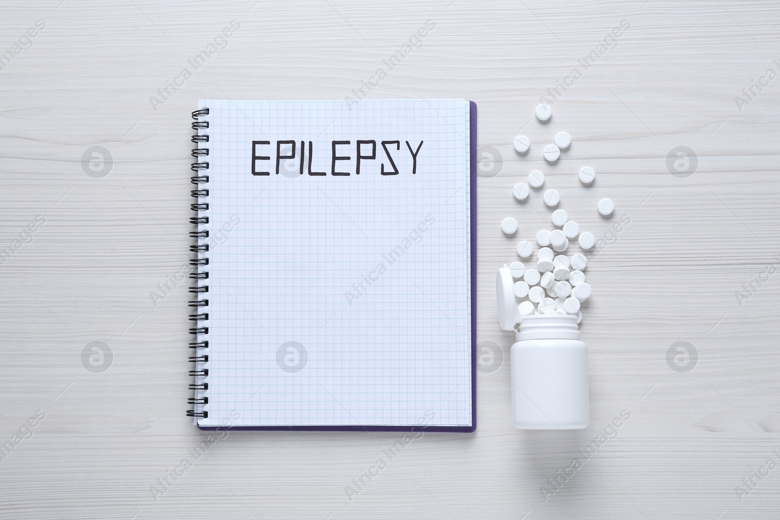 Photo of Notebook with word Epilepsy and pills on white wooden table, flat lay