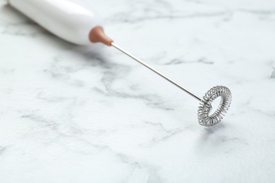 Milk frother wand on white marble table, closeup