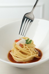 Photo of Eating tasty spaghetti with sauce from at white wooden table, closeup. Exquisite presentation of pasta dish