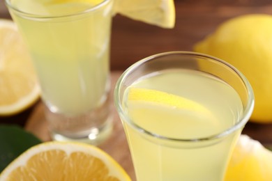Photo of Tasty limoncello liqueur with lemon on table, closeup. Space for text