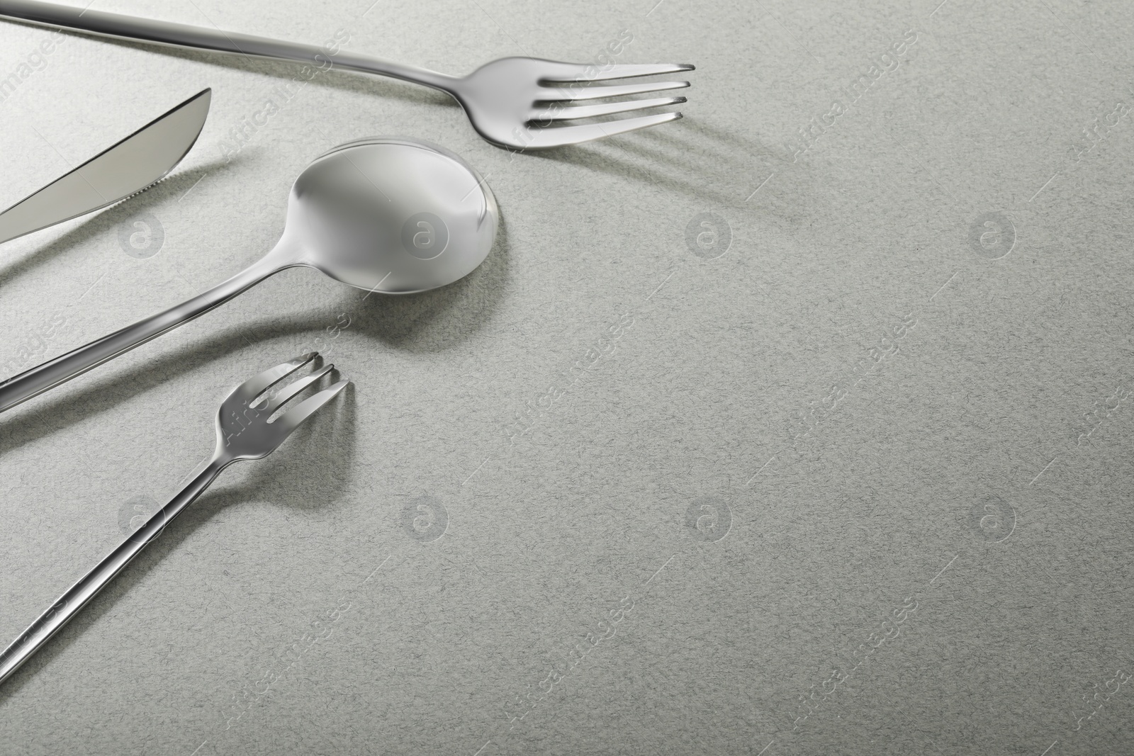 Photo of Forks, knife and spoon on grey background, space for text. Stylish cutlery set