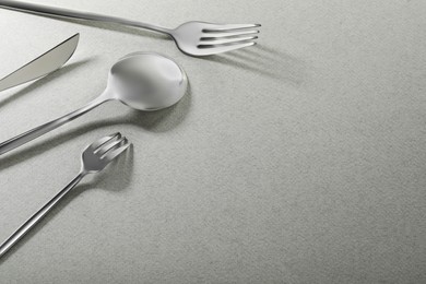 Photo of Forks, knife and spoon on grey background, space for text. Stylish cutlery set