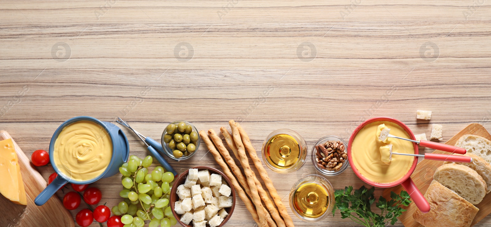 Photo of Flat lay composition with pots of cheese fondue and products on wooden table, space for text