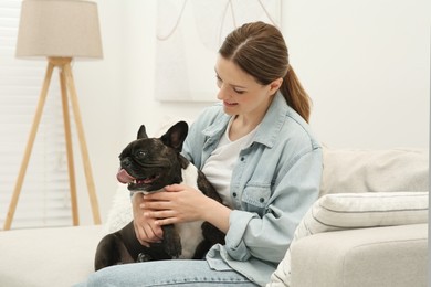 Photo of Happy woman hugging cute French Bulldog on sofa in room
