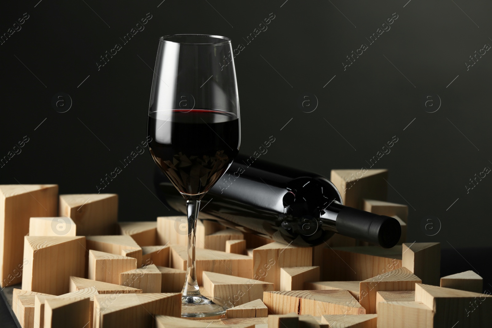 Photo of Stylish presentation of red wine in bottle and wineglass on black background