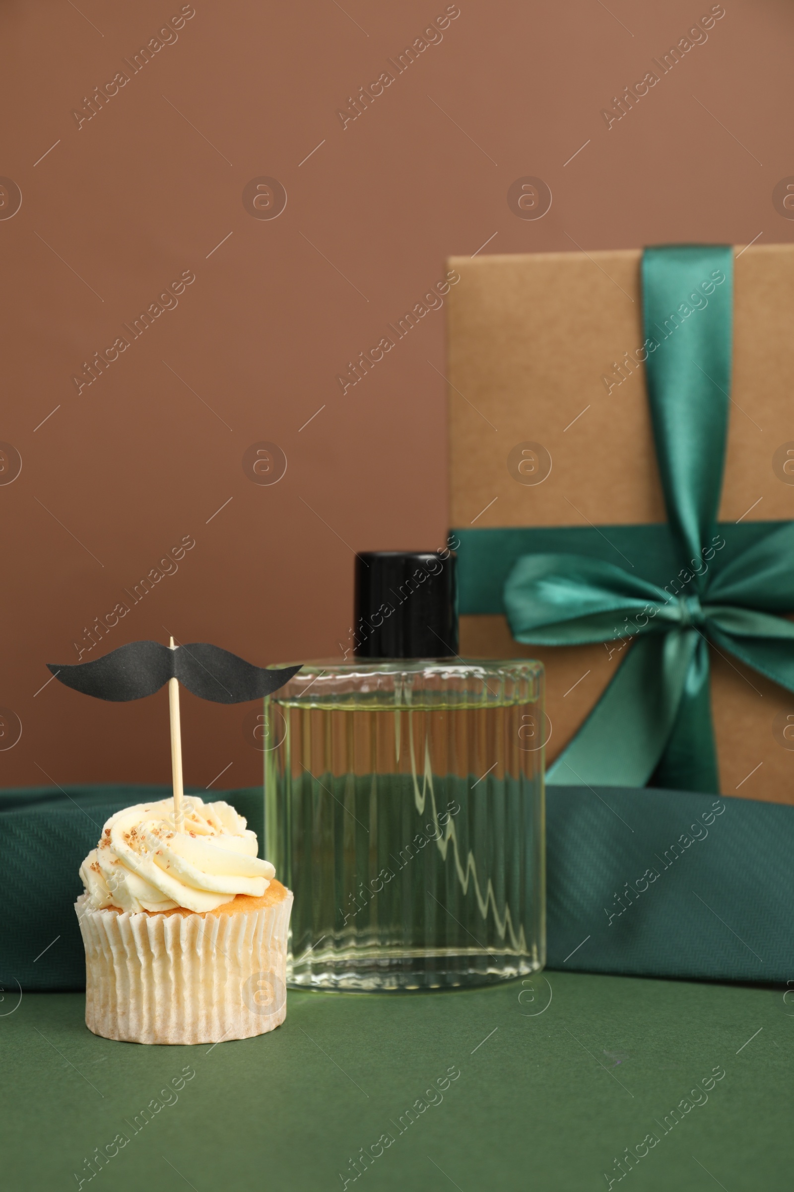 Photo of Happy Father's Day. Tasty cupcake with topper and presents on green table