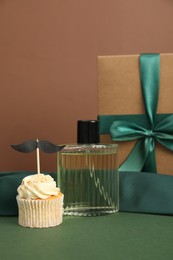 Happy Father's Day. Tasty cupcake with topper and presents on green table