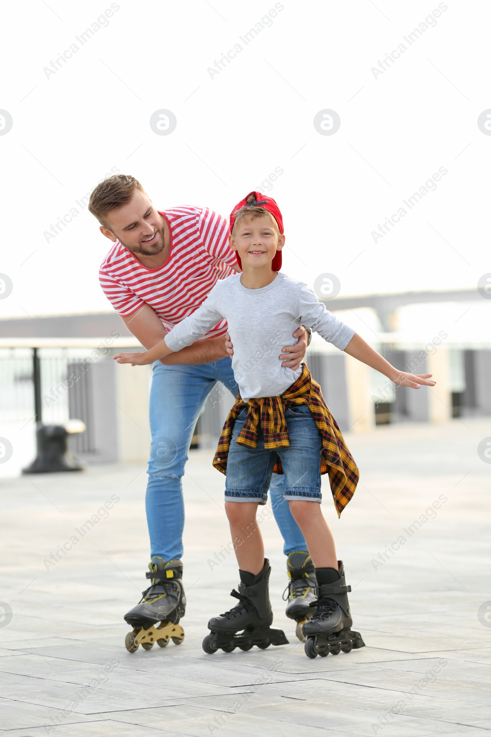 Photo of Father and son roller skating on city street