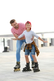 Father and son roller skating on city street