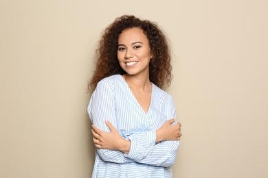 Young African-American woman with beautiful face on beige background