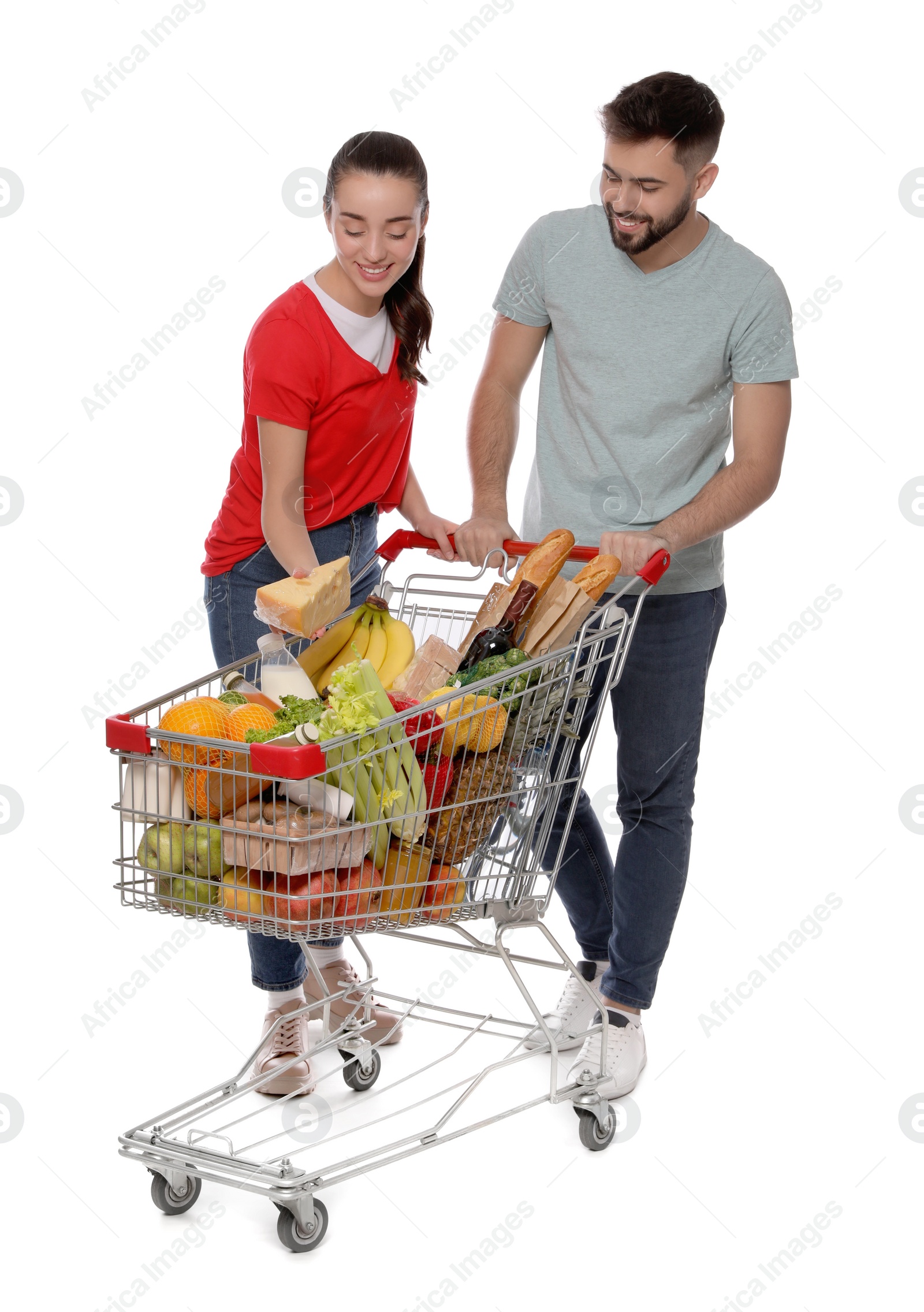 Photo of Happy couple with shopping cart full of groceries on white background