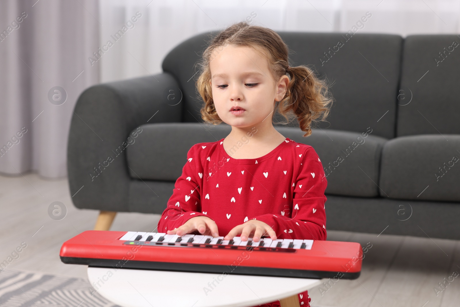 Photo of Little girl playing toy piano at home