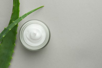 Jar with cream and aloe leaves on light grey background, flat lay. Space for text