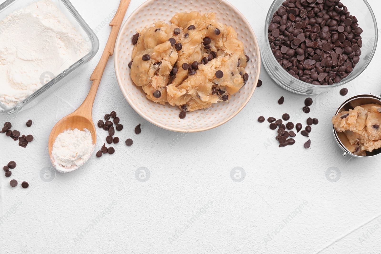 Photo of Flat lay composition with cookie dough, chocolate chips and flour on light background