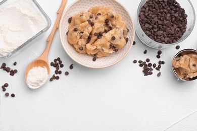 Photo of Flat lay composition with cookie dough, chocolate chips and flour on light background