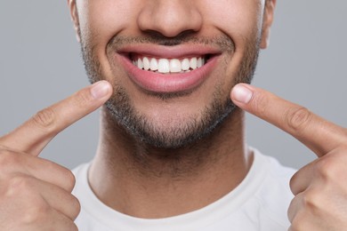 Man showing healthy gums on grey background, closeup