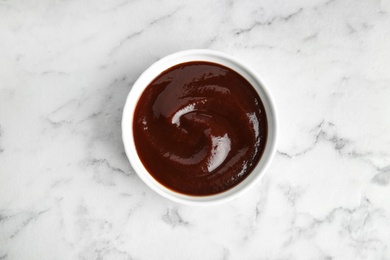 Barbecue sauce in bowl on marble background, top view