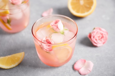 Photo of Tasty refreshing lemon drink with roses on light grey table