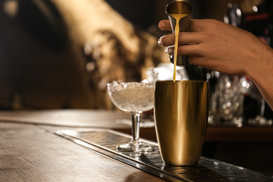 Photo of Bartender preparing fresh alcoholic cocktail at bar counter, closeup. Space for text